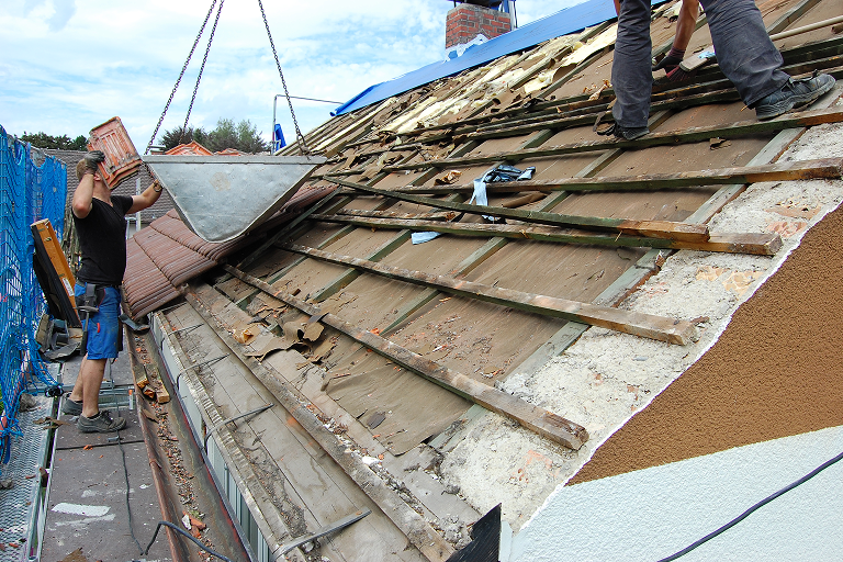 storm damage restoration team removing debris from roof